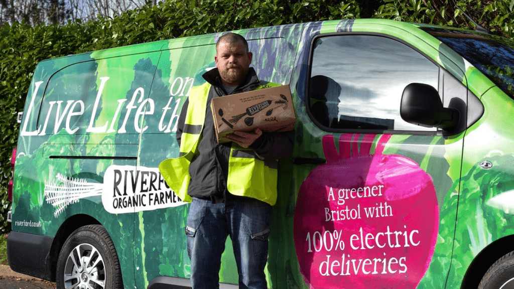 Electric delivery truck with driver holding a box of vegetables