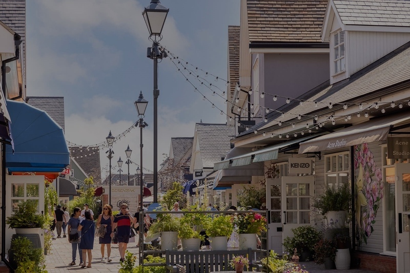Outdoor shopping street at Bicester Village with luxury brand storefronts.