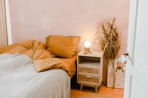 Cosy boho style bedroom: bed, night stand and a bouquet of dry grasses