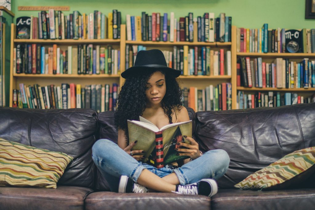girl on a sofa reading in a library