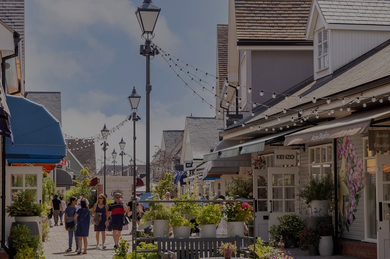 Outdoor shopping street at Bicester Village with luxury brand storefronts.